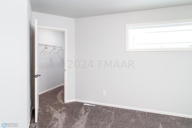 unfurnished bedroom featuring a walk in closet, baseboards, carpet, and a closet