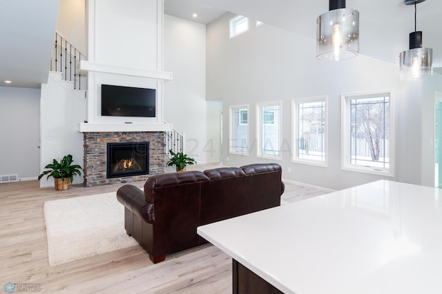 living room with recessed lighting, light wood-style flooring, a fireplace, and a towering ceiling