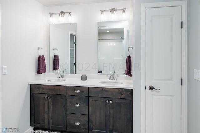 full bathroom featuring a sink, a shower, and double vanity