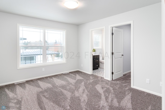 unfurnished bedroom featuring baseboards, ensuite bathroom, and carpet