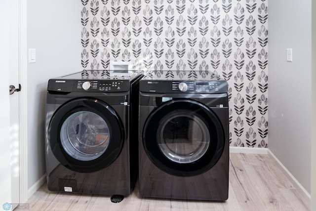 laundry area with laundry area, washer and dryer, baseboards, and wood finished floors