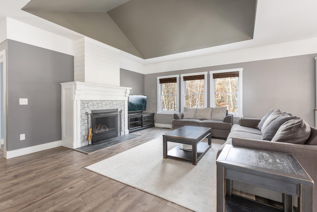 living room with high vaulted ceiling, wood finished floors, baseboards, and a premium fireplace