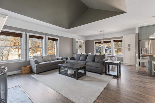 living room featuring lofted ceiling, dark wood-style floors, baseboards, and a chandelier