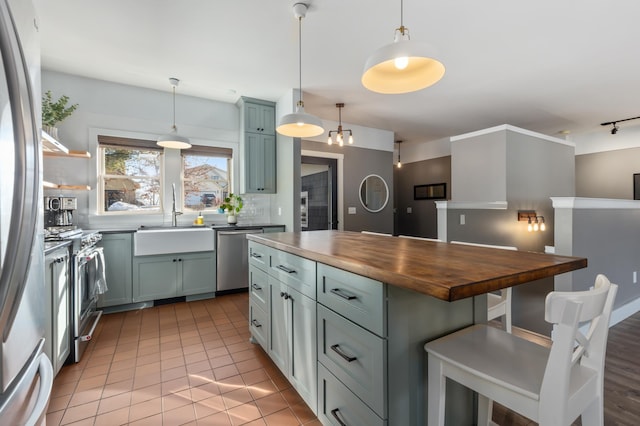 kitchen with tasteful backsplash, a breakfast bar, stainless steel appliances, wooden counters, and a sink