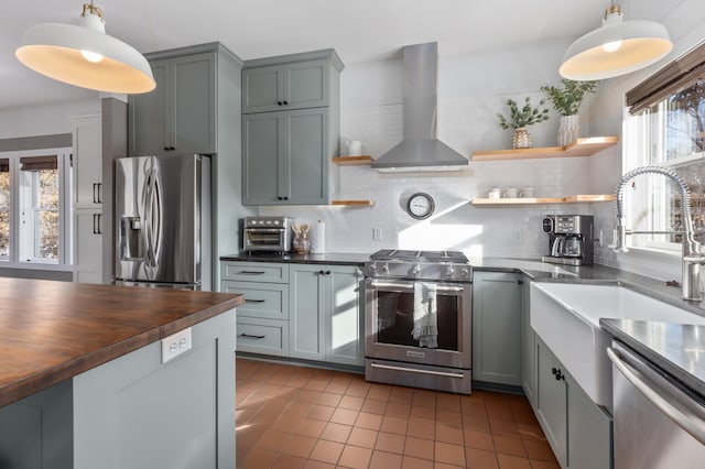 kitchen featuring open shelves, tasteful backsplash, appliances with stainless steel finishes, butcher block countertops, and wall chimney exhaust hood