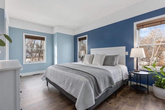 bedroom featuring hardwood / wood-style floors, multiple windows, and baseboards