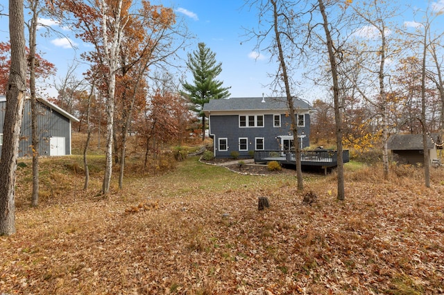 rear view of property with a deck and an outbuilding