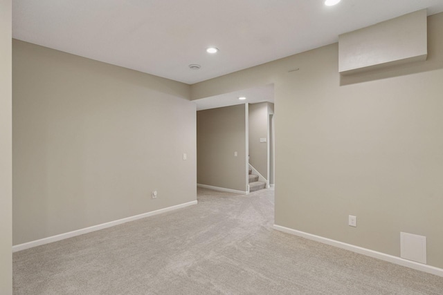 empty room featuring stairs, recessed lighting, baseboards, and light carpet