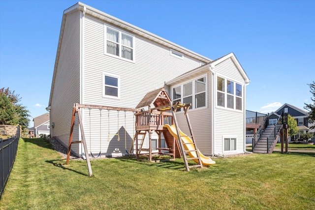 back of house with stairs, a playground, a lawn, and fence