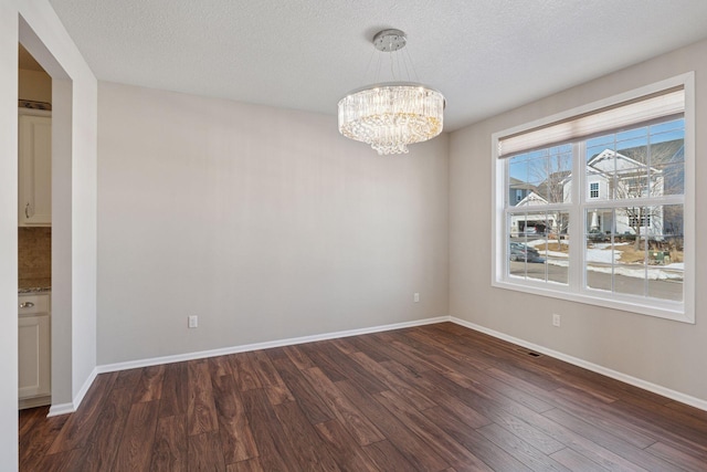 unfurnished dining area featuring a notable chandelier, baseboards, and dark wood-type flooring