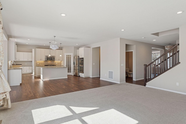 unfurnished living room with visible vents, baseboards, dark wood finished floors, recessed lighting, and stairs