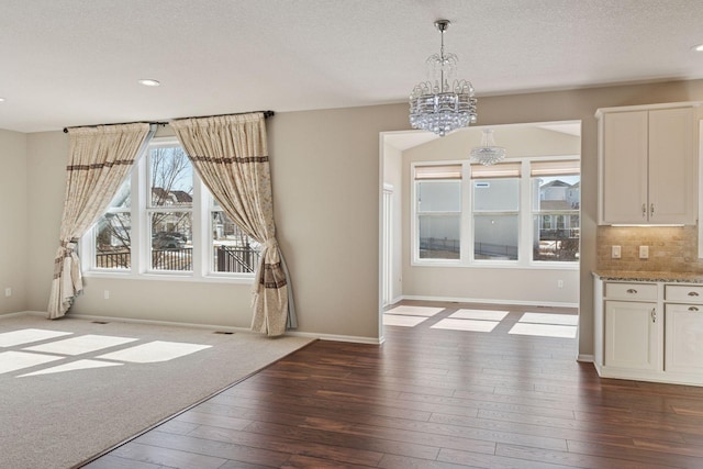 unfurnished dining area with baseboards, recessed lighting, dark wood-type flooring, a textured ceiling, and a notable chandelier