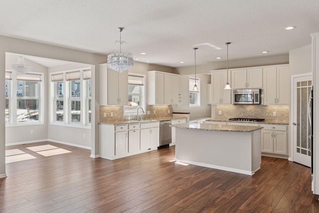 kitchen featuring a sink, a kitchen island, dark wood finished floors, white cabinetry, and stainless steel appliances