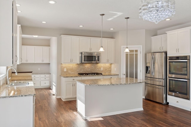 kitchen with a sink, white cabinetry, appliances with stainless steel finishes, decorative backsplash, and dark wood-style flooring