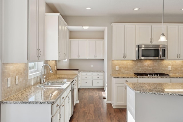 kitchen with a sink, light stone counters, dark wood-style floors, white cabinetry, and stainless steel appliances