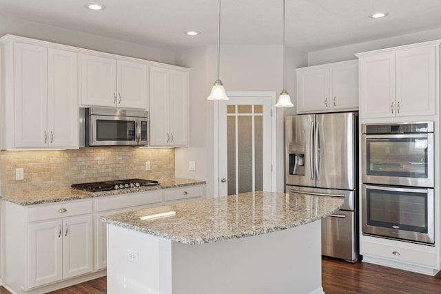 kitchen with stainless steel appliances, dark wood-type flooring, white cabinets, tasteful backsplash, and a center island