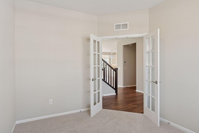 carpeted spare room featuring visible vents, baseboards, and french doors