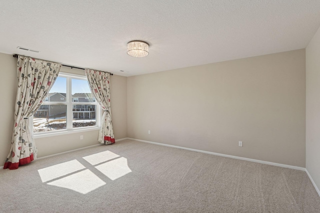 spare room with visible vents, baseboards, carpet, and a textured ceiling