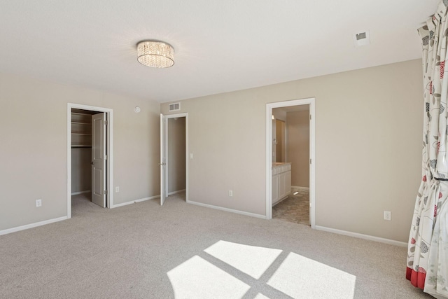 unfurnished bedroom with light carpet, visible vents, a spacious closet, and baseboards