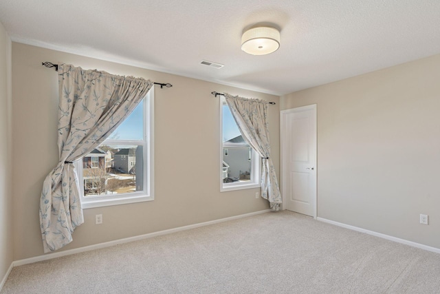 carpeted spare room with baseboards, visible vents, and a textured ceiling