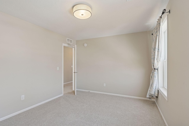 unfurnished room featuring visible vents, baseboards, and light colored carpet