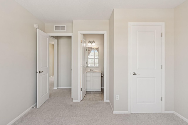 unfurnished bedroom with light carpet, visible vents, and baseboards