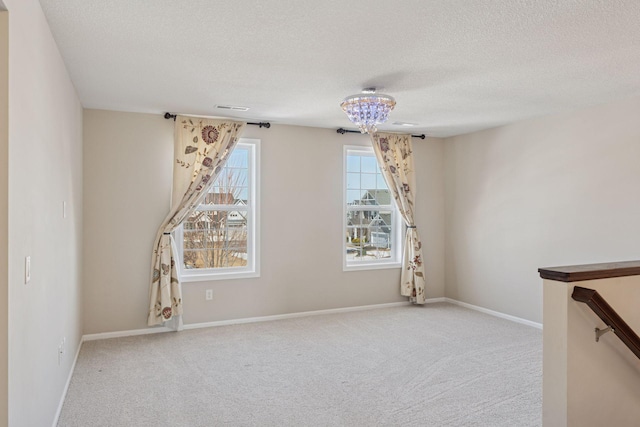 spare room with carpet, baseboards, and a textured ceiling