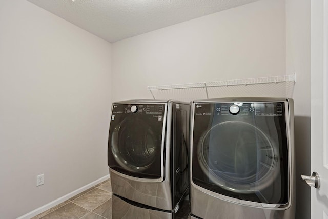 washroom featuring baseboards, laundry area, tile patterned flooring, a textured ceiling, and washer and clothes dryer