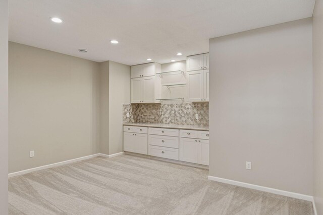 kitchen with decorative backsplash, light colored carpet, light countertops, and baseboards