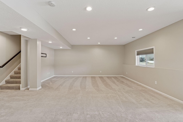 basement featuring recessed lighting, baseboards, light colored carpet, and stairs