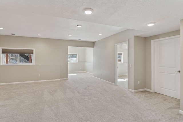 spare room featuring recessed lighting, light colored carpet, a textured ceiling, and baseboards