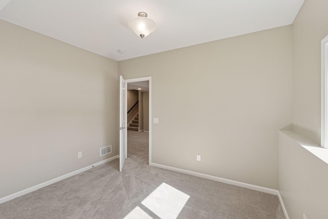 empty room featuring baseboards, light carpet, and visible vents