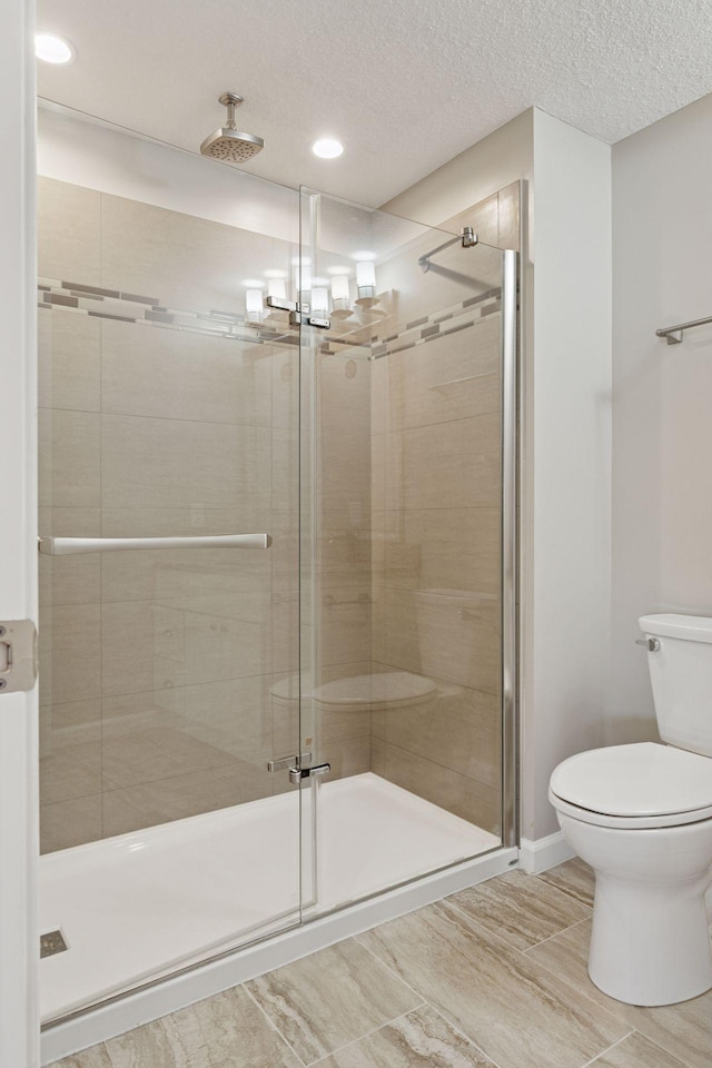 bathroom with a stall shower, toilet, and a textured ceiling