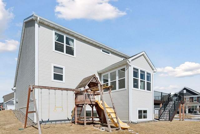 rear view of property featuring stairs, a playground, and a wooden deck