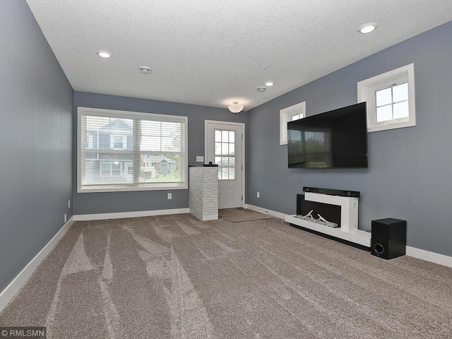 unfurnished living room featuring carpet floors, baseboards, and a textured ceiling