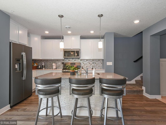 kitchen featuring white cabinets, appliances with stainless steel finishes, dark wood-style flooring, light countertops, and backsplash