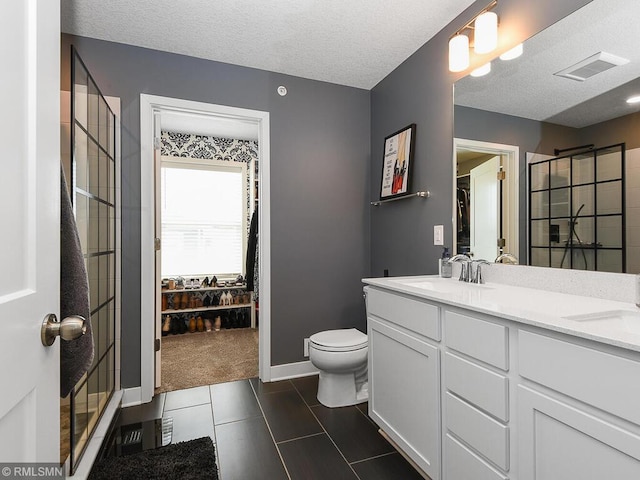 full bath with a shower stall, a textured ceiling, visible vents, and a sink