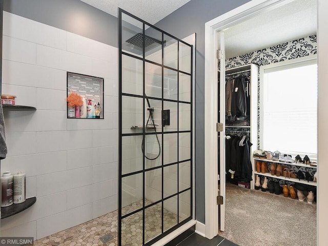 full bath featuring a spacious closet, a textured ceiling, and a walk in shower