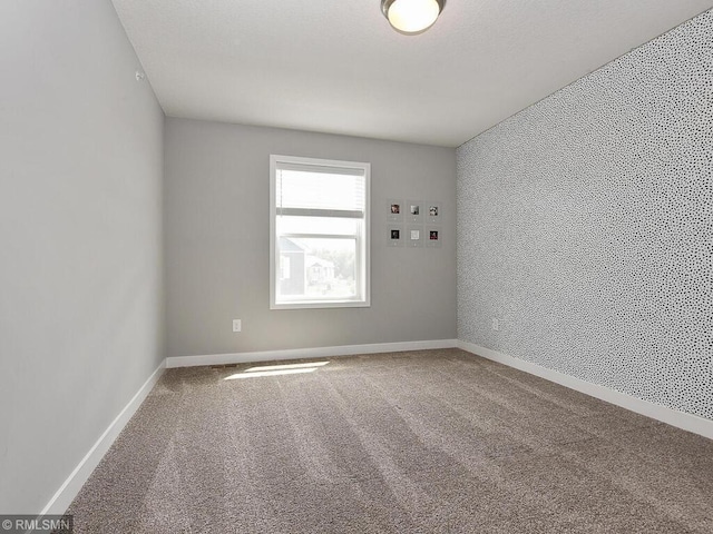 unfurnished room with baseboards and carpet flooring