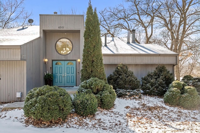 snow covered property entrance featuring a chimney