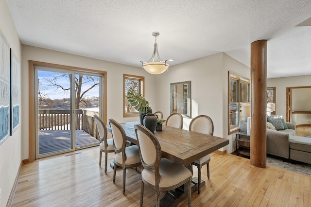 dining space featuring a textured ceiling, visible vents, light wood-style flooring, and baseboards