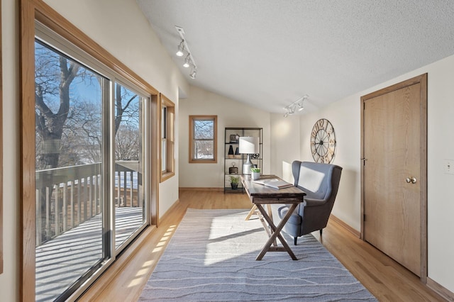 office featuring a textured ceiling, light wood finished floors, vaulted ceiling, and rail lighting