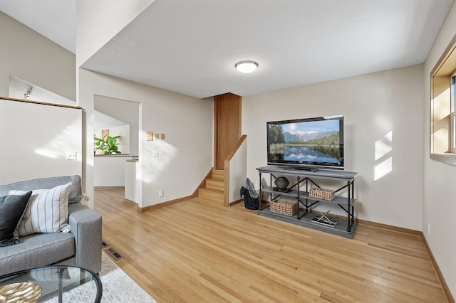 living area with light wood-type flooring, baseboards, stairs, and visible vents