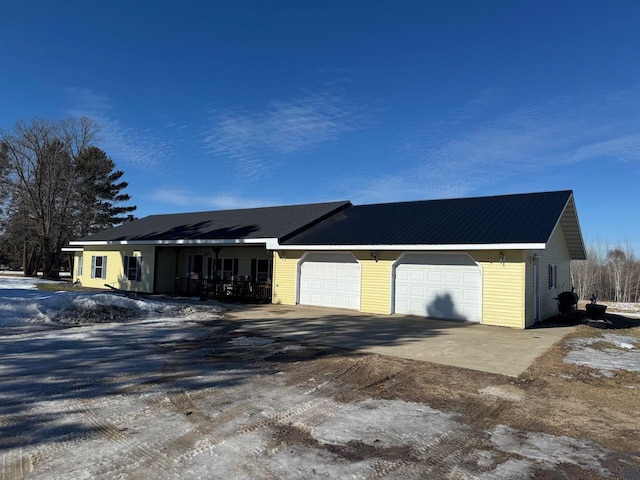 single story home featuring a garage, driveway, and metal roof