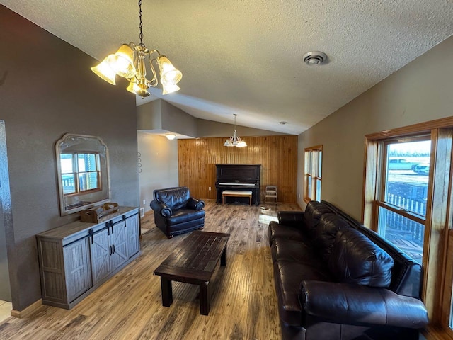 living room with vaulted ceiling, visible vents, a notable chandelier, and wood finished floors