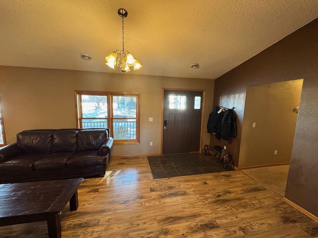 entrance foyer featuring vaulted ceiling, a textured ceiling, wood finished floors, and an inviting chandelier