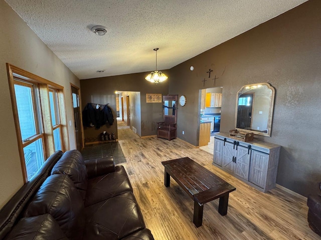 living area featuring visible vents, vaulted ceiling, a textured ceiling, wood finished floors, and baseboards