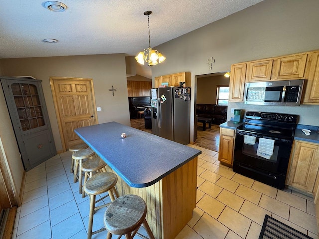 kitchen with a kitchen island, a kitchen breakfast bar, vaulted ceiling, appliances with stainless steel finishes, and dark countertops