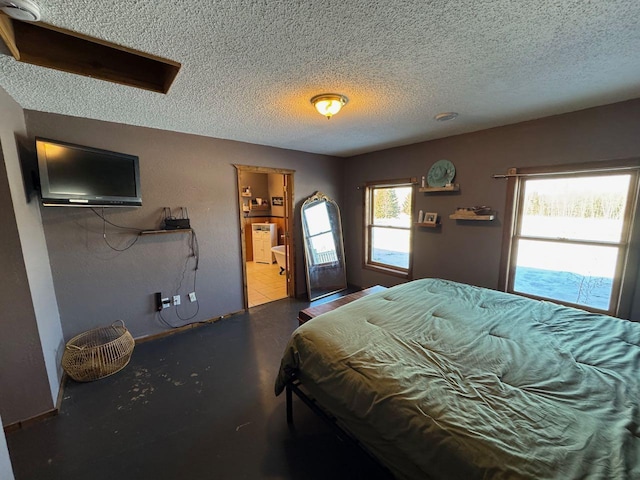 bedroom with ensuite bath, concrete floors, and a textured ceiling