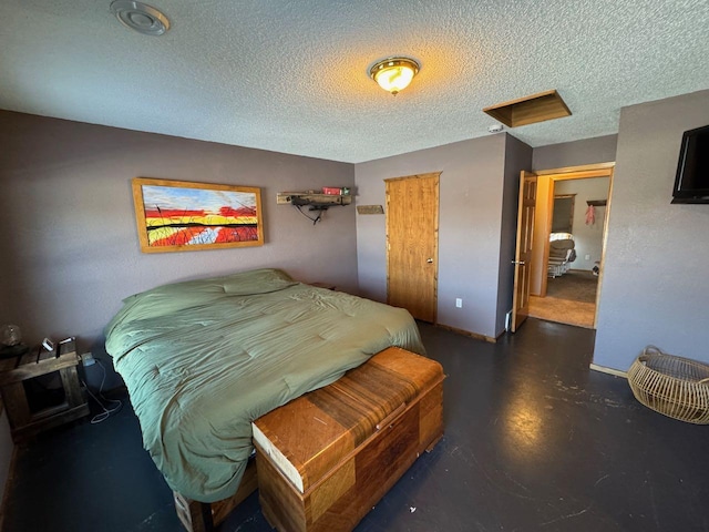 bedroom featuring finished concrete floors, attic access, a textured ceiling, and baseboards